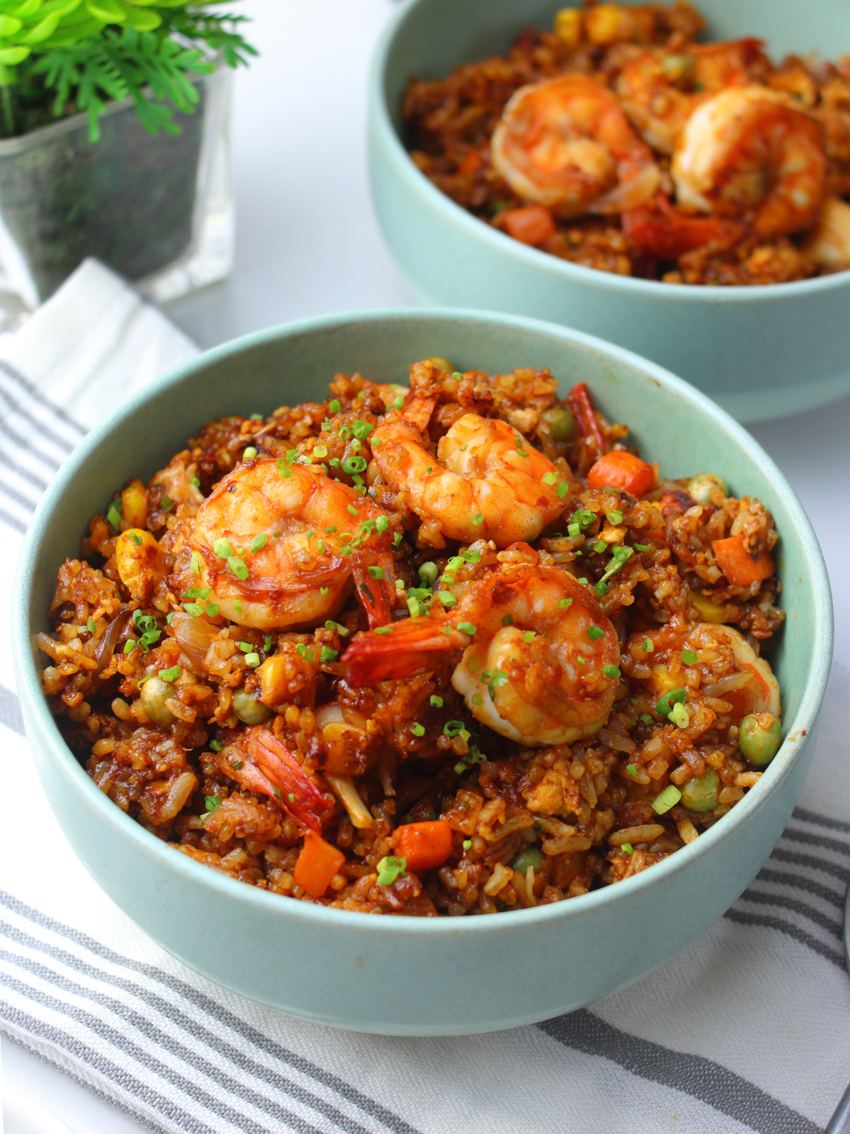 Chinese shrimp fried rice in a green bowl topped with scallions.