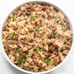Nigerian rice and beans in a white plate topped with chopped parsley.