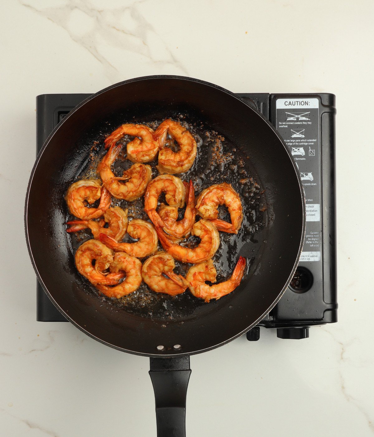 Prawns cooked in a black pan with oil.