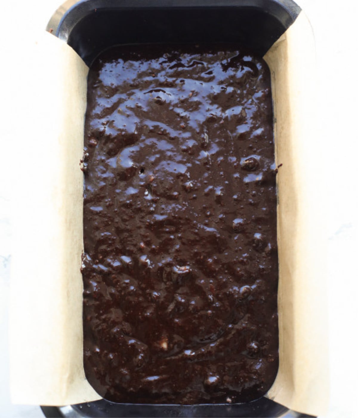 Chocolate banana bread mixture in a lined loaf tin.