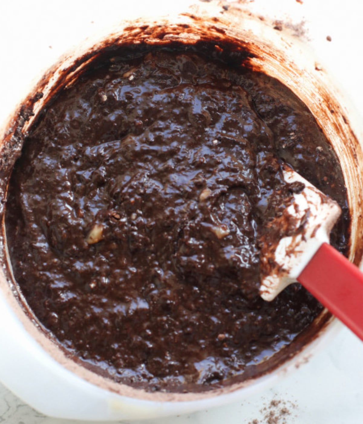 Egg, mashed banana, cocoa powder, flour mixed in a bowl with a spatula.