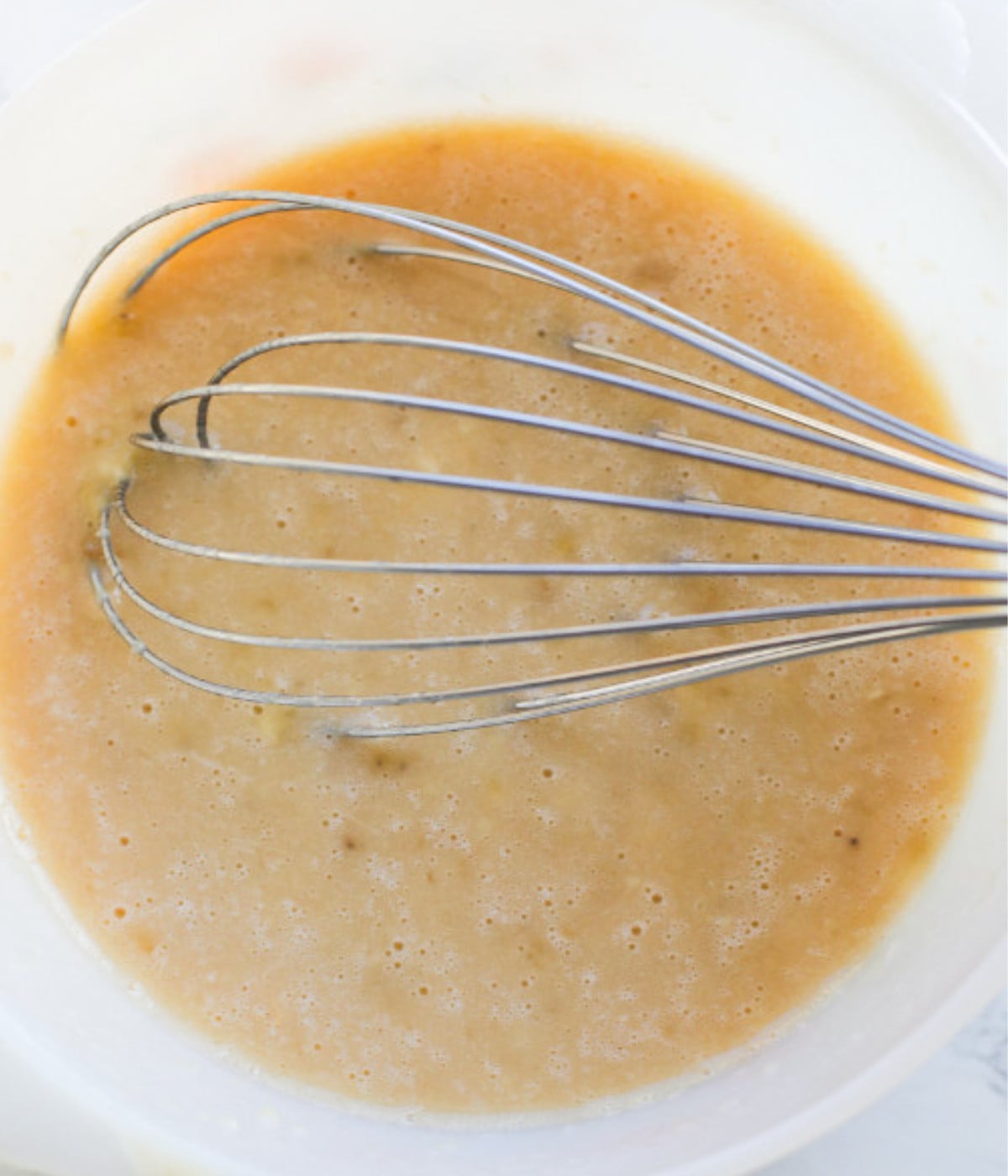 Mixed oil, eggs and mashed bananas mixed in a bowl.