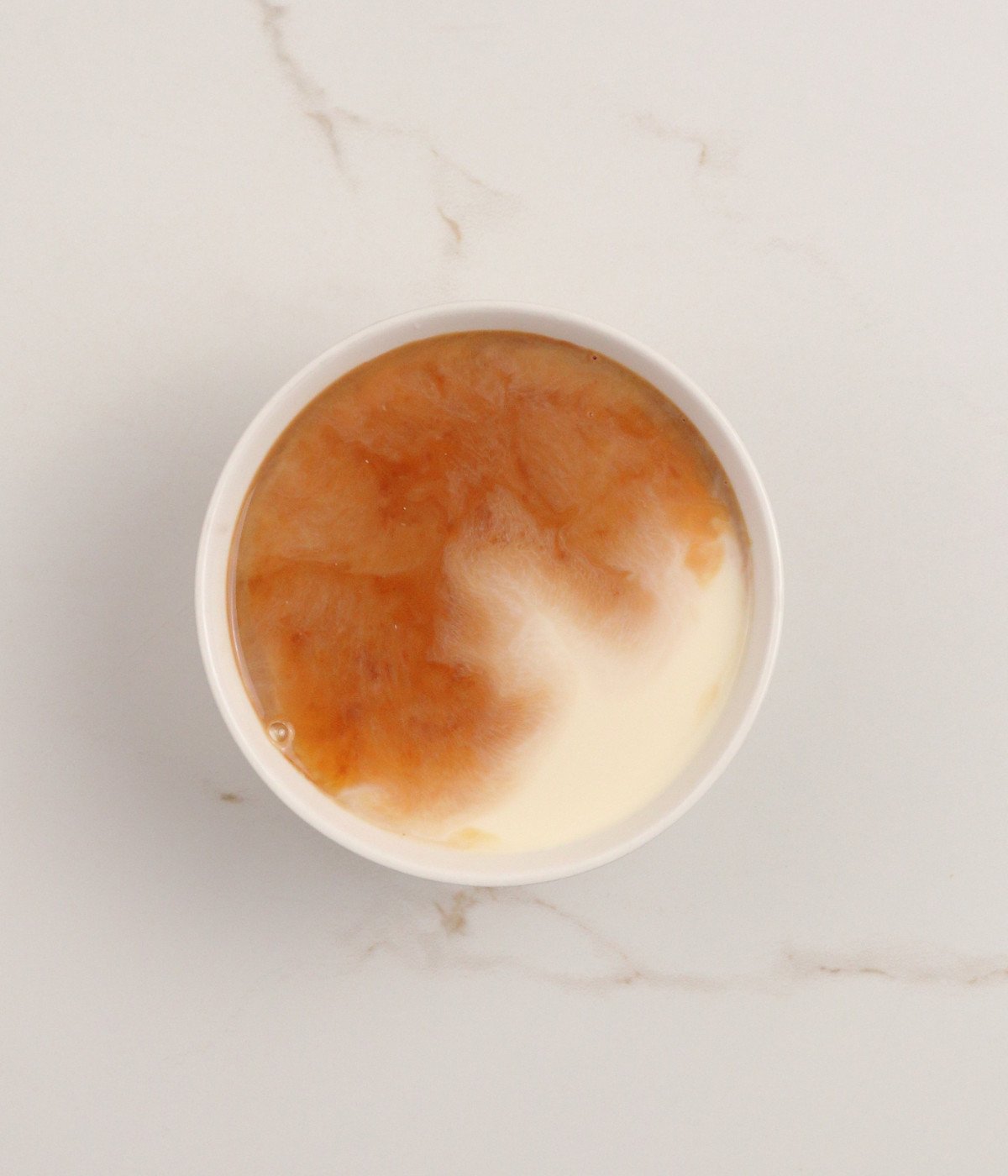Milk, eggs and vanilla extract in a white bowl.