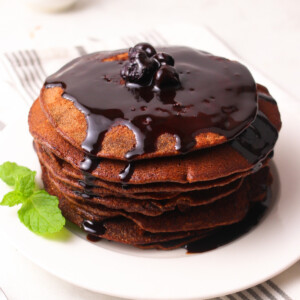 Wholemeal chocolate pancakes on a white plate with chocolate sauce.