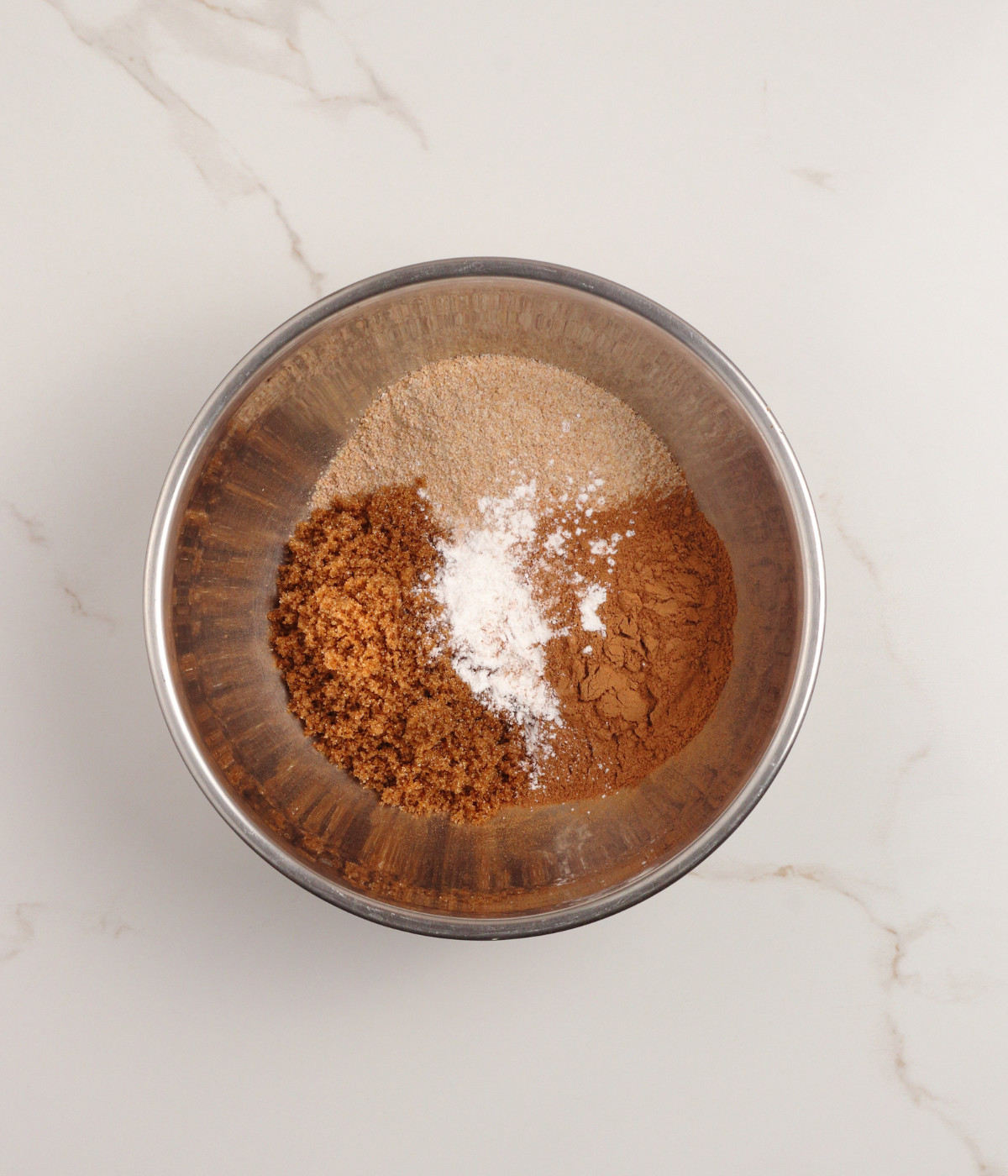 Wholemeal flour, brown sugar, leavening agents and salt in a silver bowl.