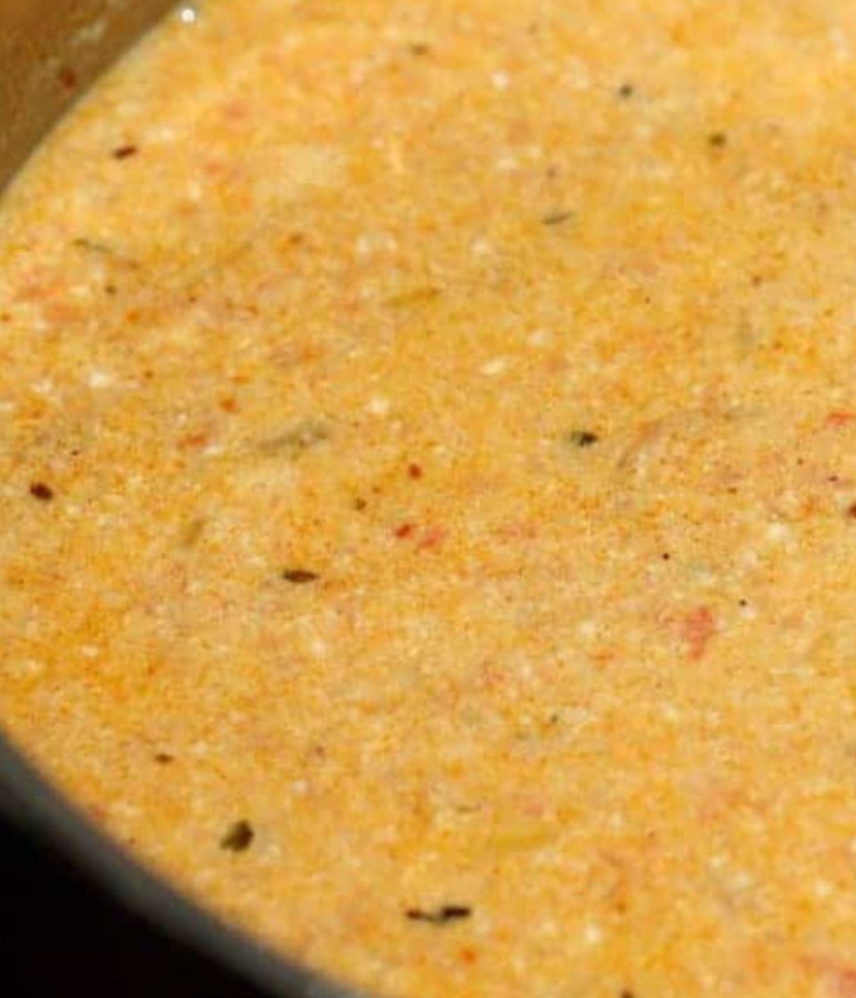 Blended tomatoes, coconut milk and seasoning cooking in a silver pot.