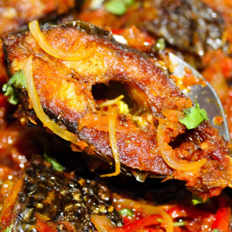 Grilled fish piece with onions and fresh herbs on top.