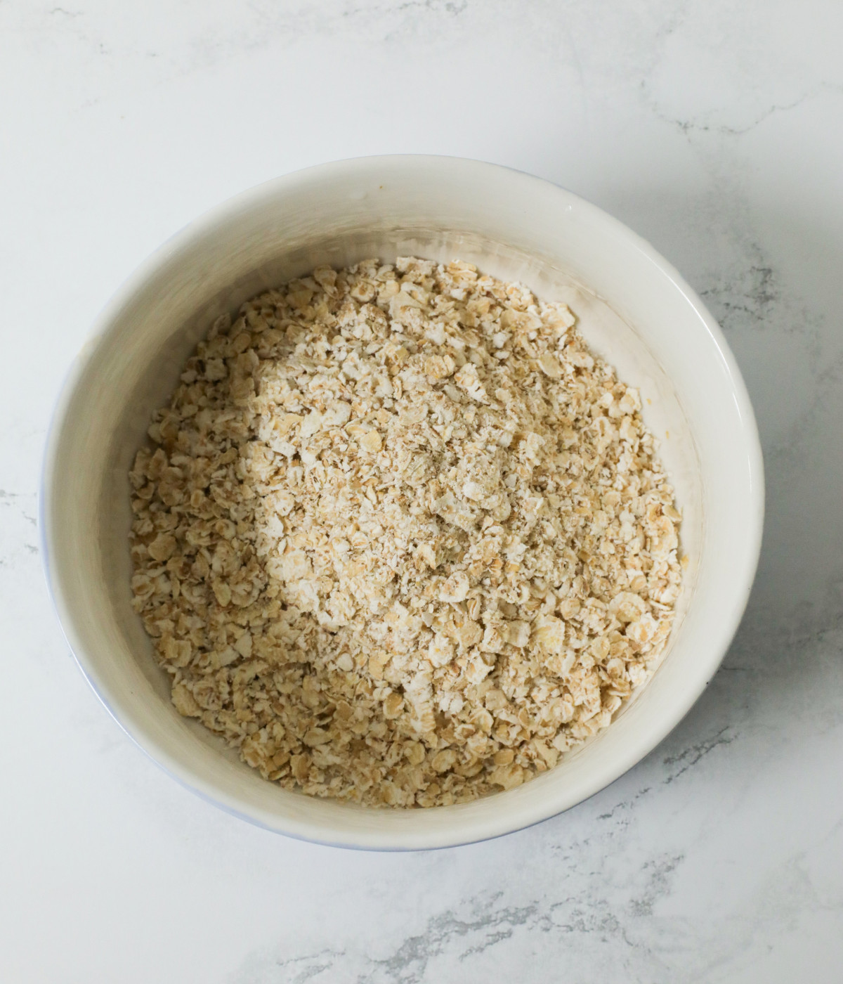Uncooked oats in a white bowl.