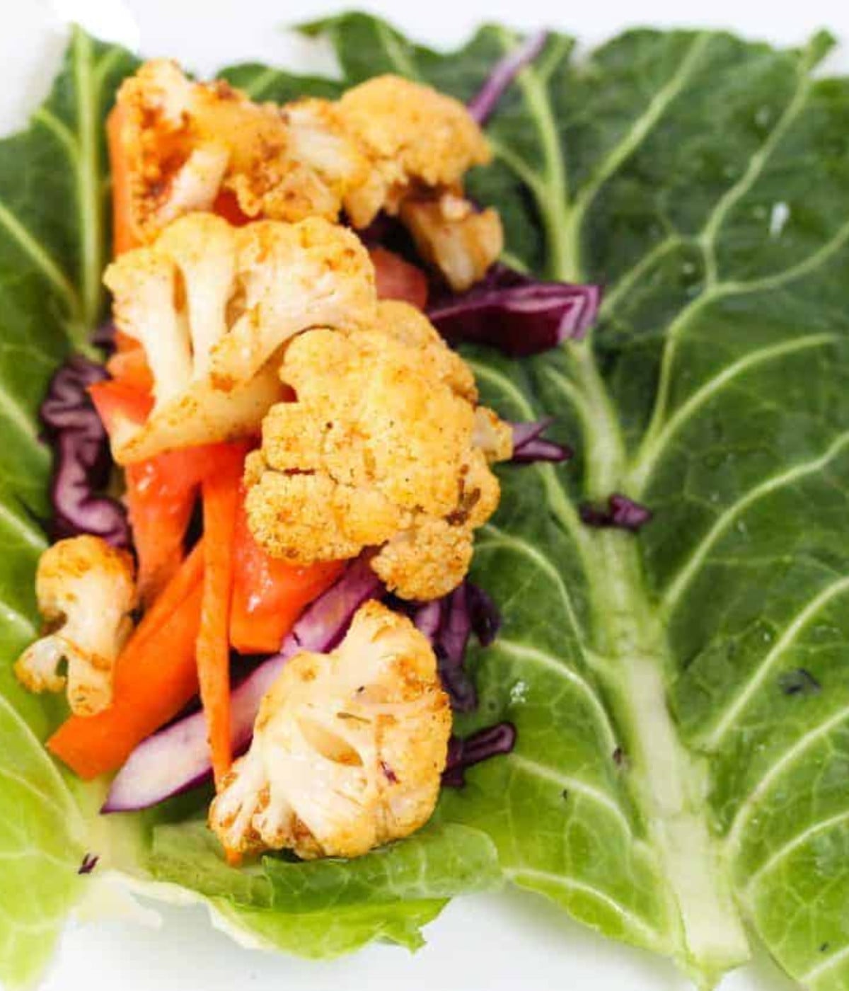 Cajun cauliflowers, cabbage and red capsicum peppers in collard green wrap.
