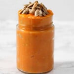 Pumpkin sauce in a jar topped with seeds.