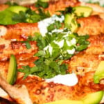 Veg enchiladas topped with sour cream, avocado and fresh herbs.