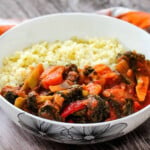 Broccoli, carrots, onions and stew with bulgur wheat in a white bowl.