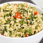 Bulgur, tomato, and fresh herbs in a white bowl