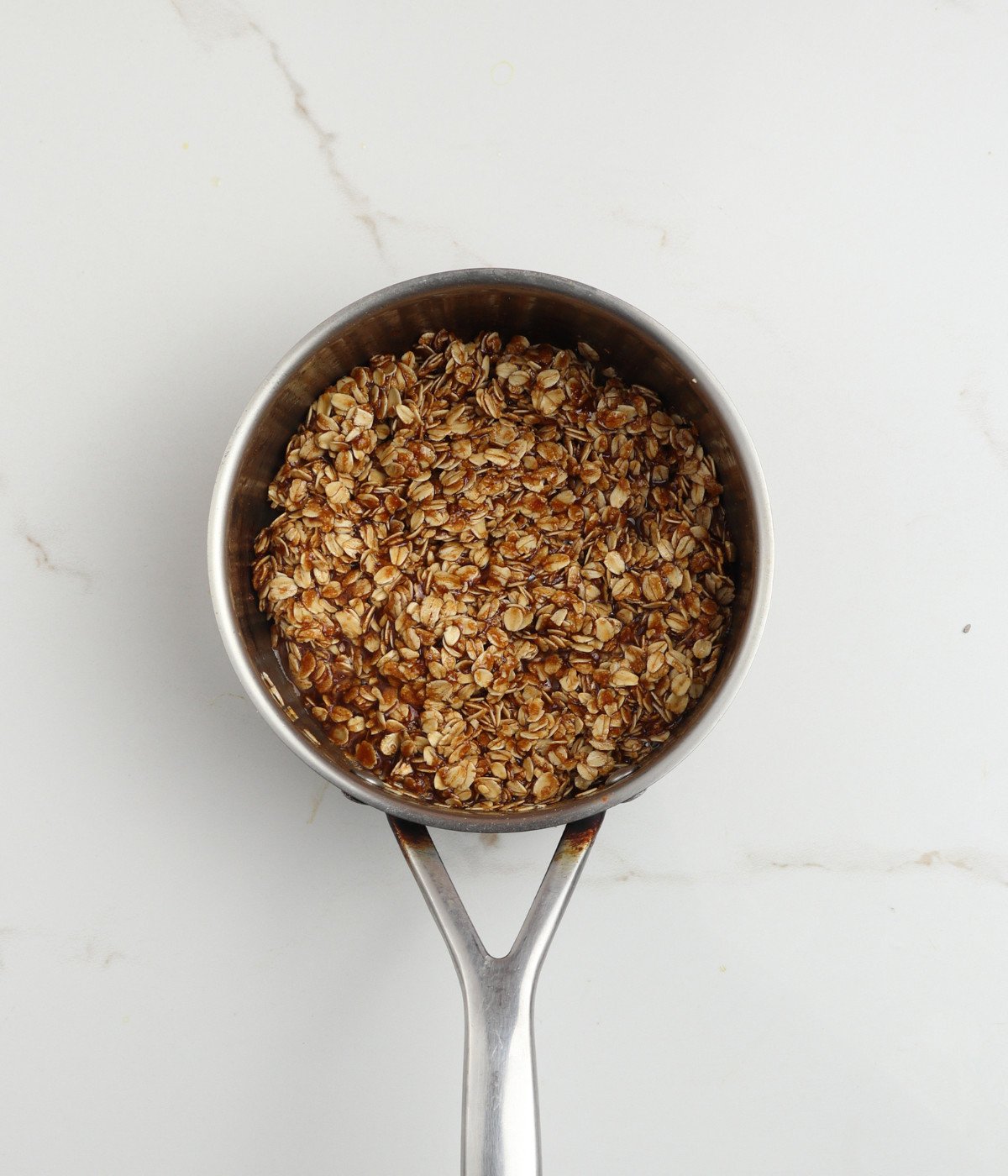 Melted white chocolate, oats, cinnamon, and salt mixed in a pot.