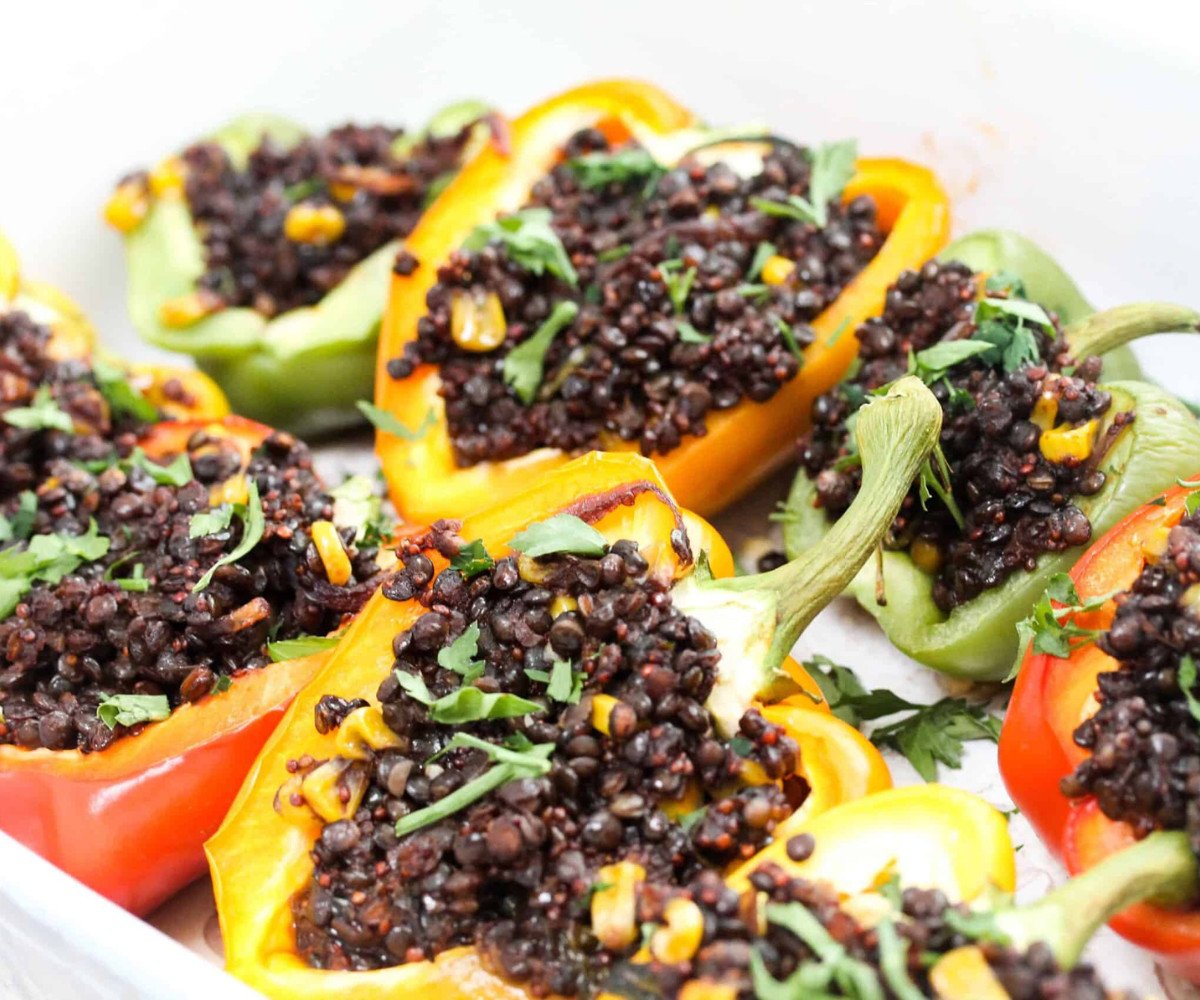 Stuffed capsicum peppers in a white oven dish topped with fresh parsley.