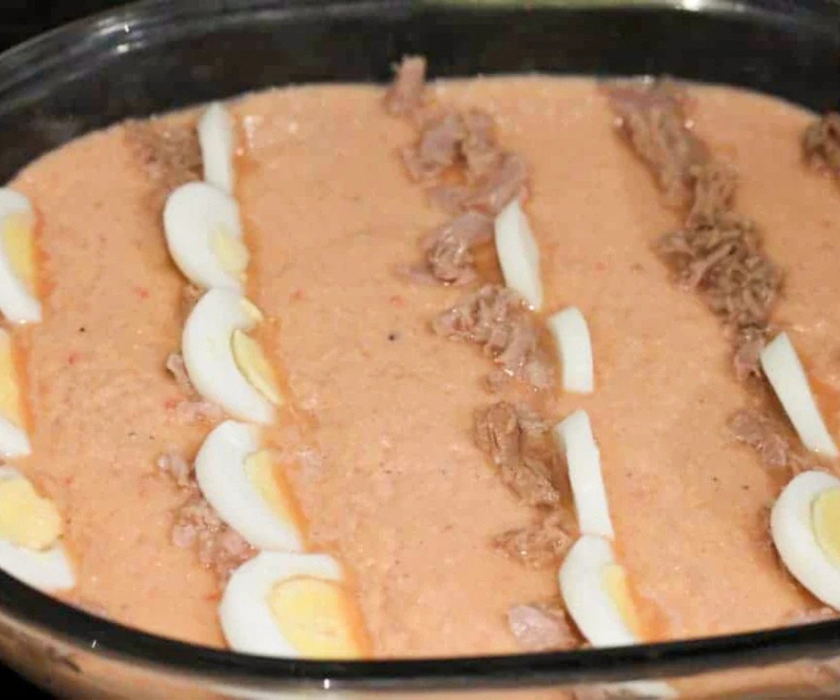 Blended moin moin mix in a glass dish topped with boiled eggs and tuna.