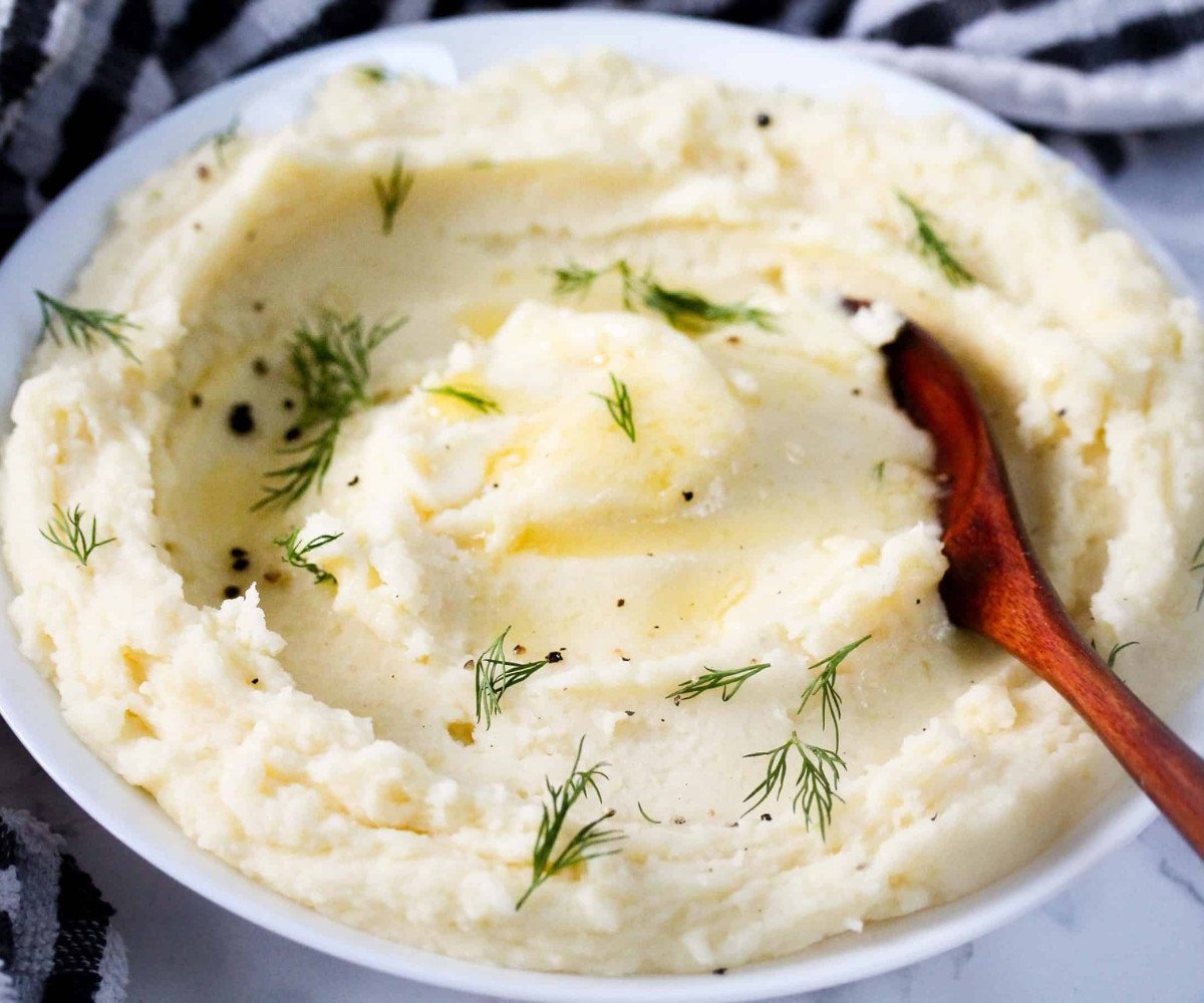 Mashed potatoes in a white plate with herbs.
