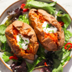 Roasted sweet potatoes topped with sour cream and chimes on a bed of salad.