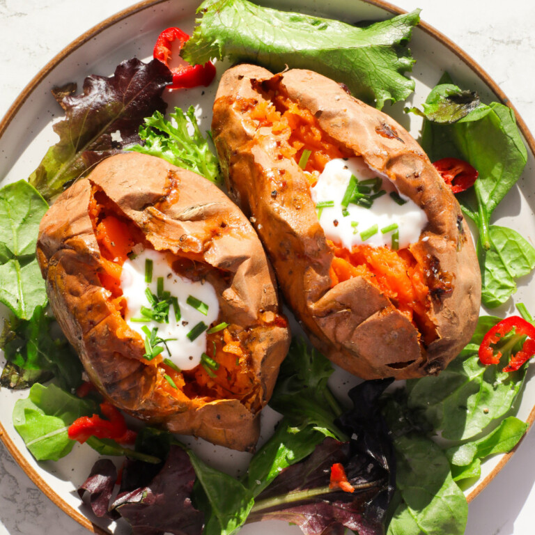 Roasted sweet potatoes topped with sour cream and chimes on a bed of salad.