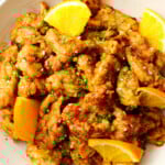 Chinese orange chicken topped with orange slices, scallions and sesame seeds.