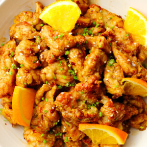 Chinese orange chicken topped with orange slices, scallions and sesame seeds.