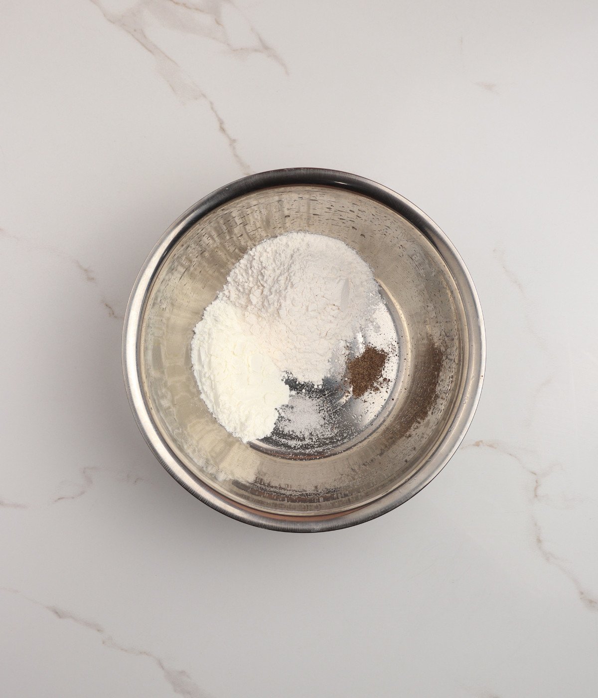 Flour, cornstarch, salt and black pepper in a silver bowl.