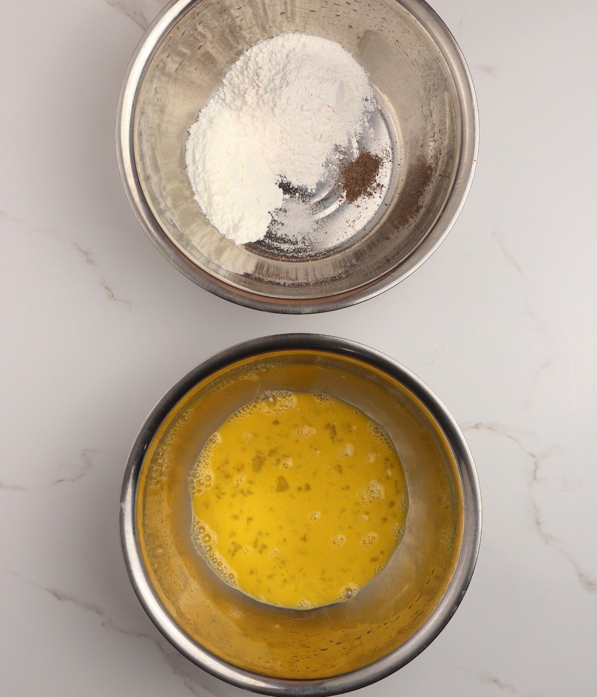 Flour, cornstarch, salt, black pepper and eggs in silver bowls.