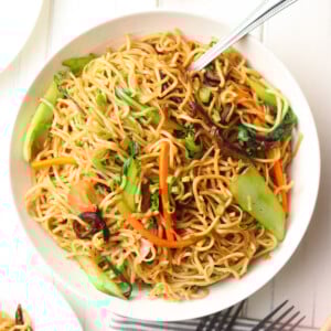 Chinese vegetable noodles in a white plate with a fork.