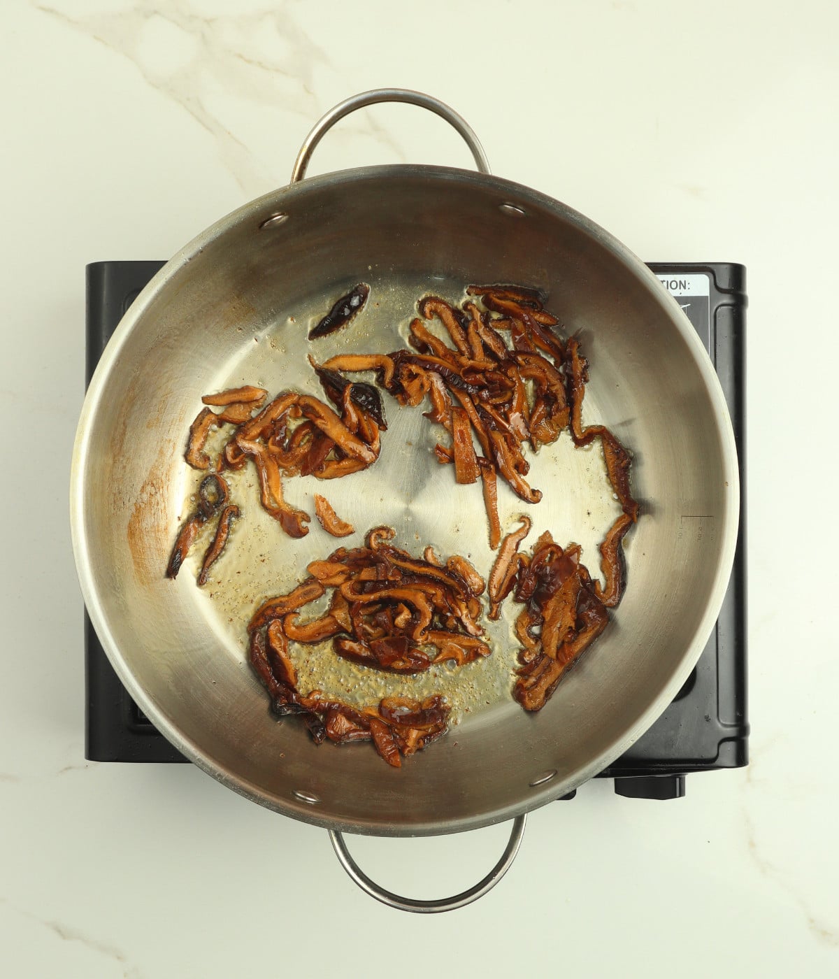 Mushroom and oil in a silver wok.