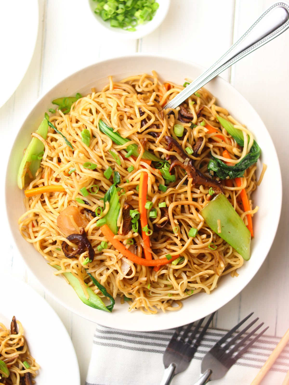  Chinese-style vegetable noodles in a white bowl with silver fork.