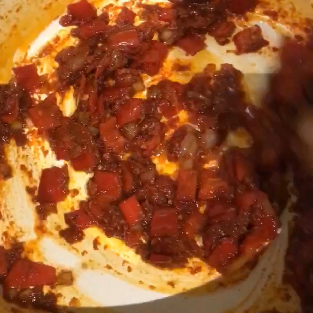 Onions, red peppers and tomato puree stirred in a pot.