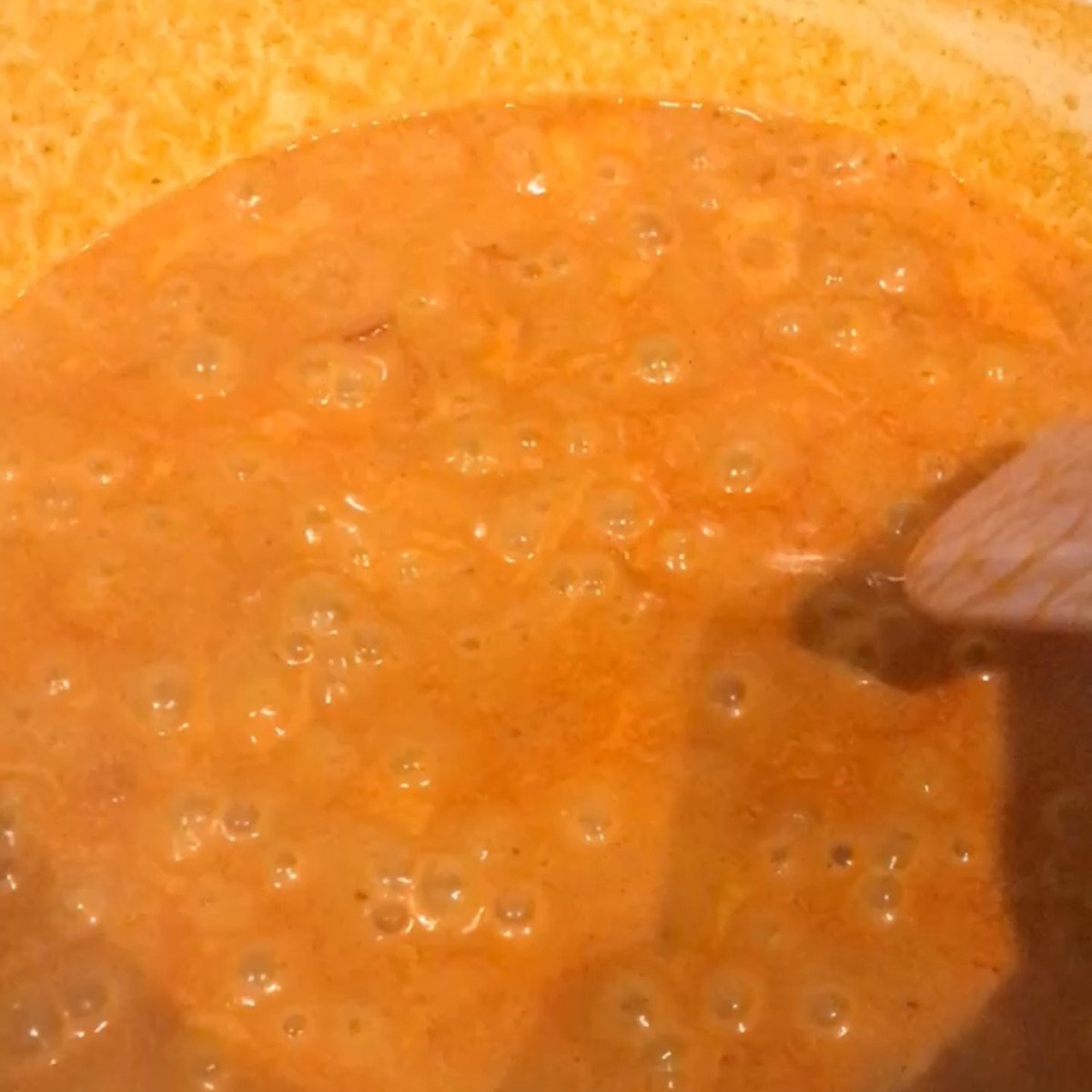 Onions, red peppers, heavy cream and tomato puree stirred in a pot. 