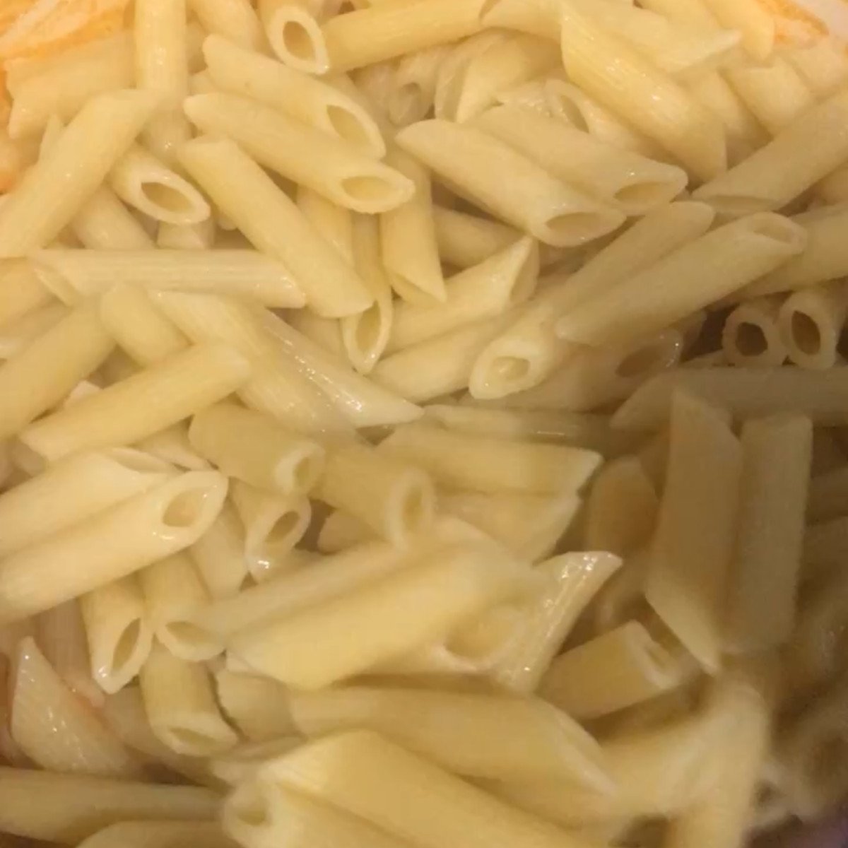 Onions, red peppers, heavy cream, penne pasta and tomato puree stirred in a pot.