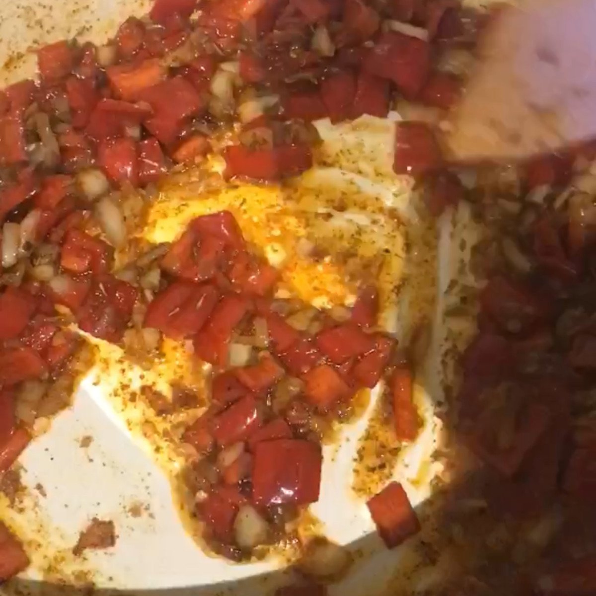 Onions, red peppers stirred in a pot.