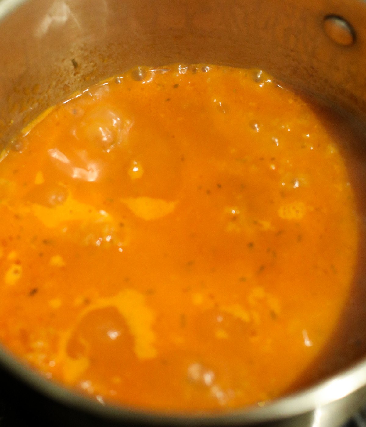 Blended tomato mixture, and seasoning mixed in a silver pot.