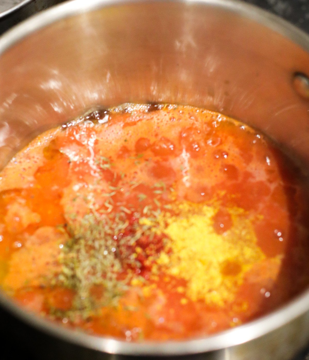 Blended tomato mixture, seasoning and vegetable oil in a silver pot.