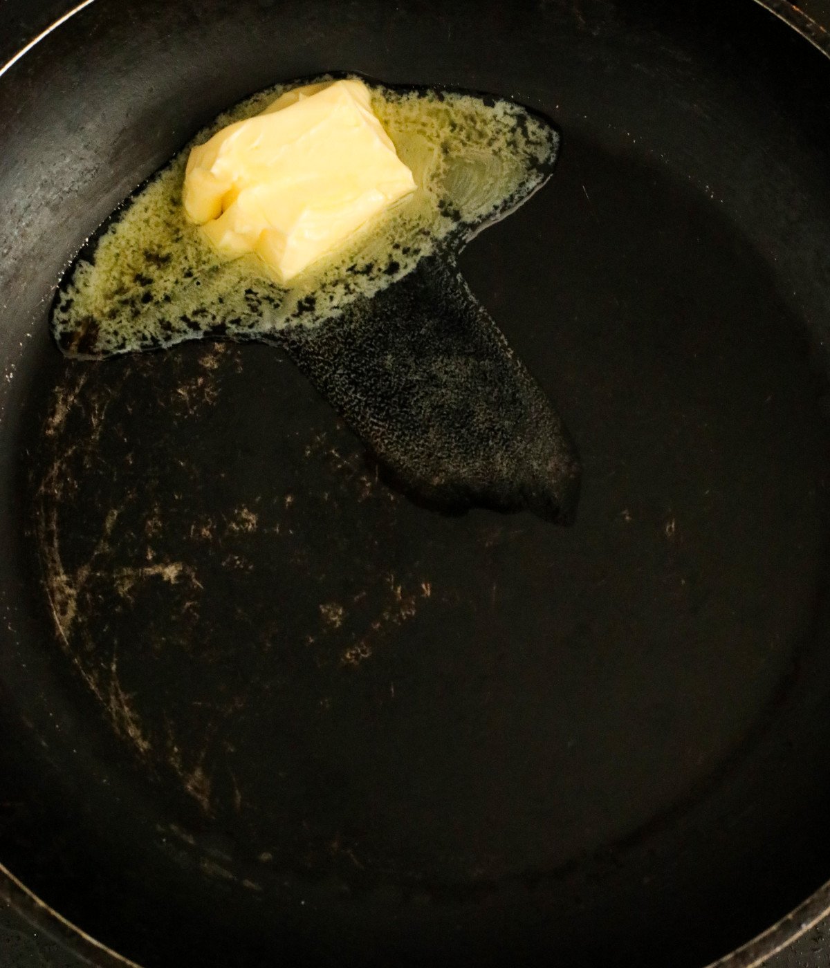 Butter melting in a black pan.