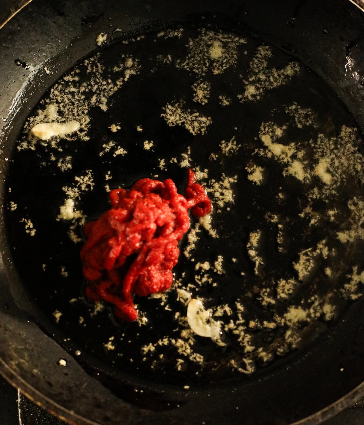 Butter, minced garlic and tomato puree in a black pan.
