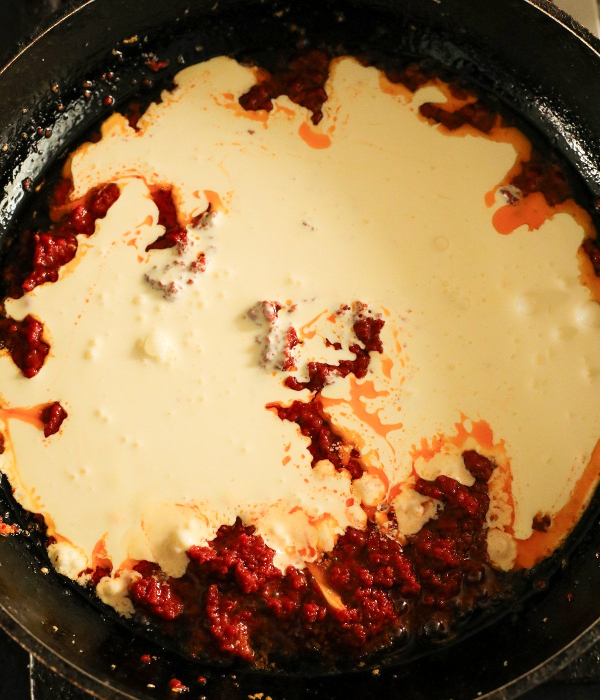 Butter, minced garlic, heavy cream and tomato puree in a black pan.