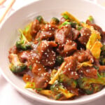 Chinese style beef, broccoli and sesame seeds in a white plate.