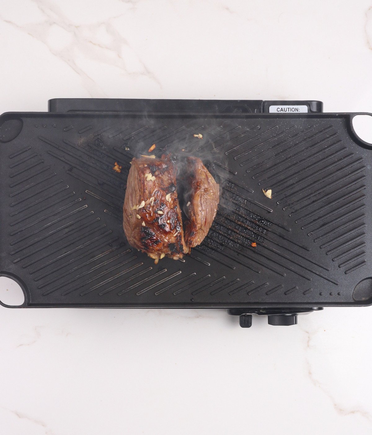 Sirloin steak cooking on a grill.