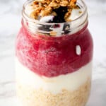 Berry, yogurt, granola and oats in a jar.