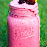 Blackberry smoothie in glass jar on grass.