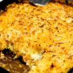 Ground beef cooked with mashed potatoes and cheese in an oven dish.