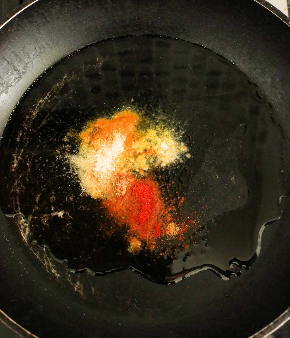 Oil and seasoning heated in a black pan.