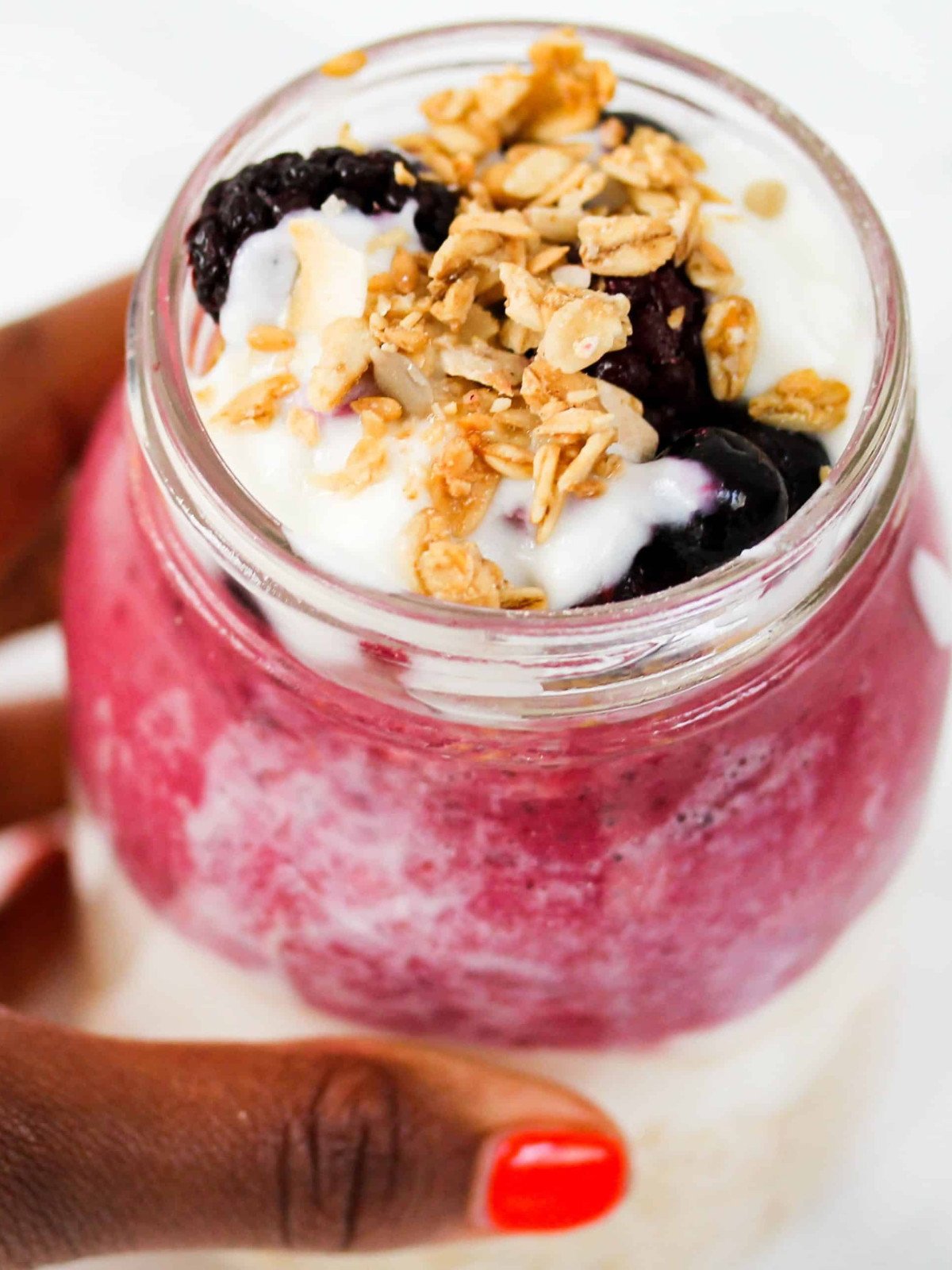 Overnight oats berry oats in a glas jar topped with yogurt and granola.
