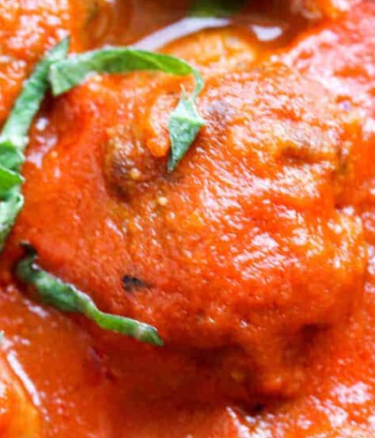 Baked meatball in tomato sauce with fresh herbs.