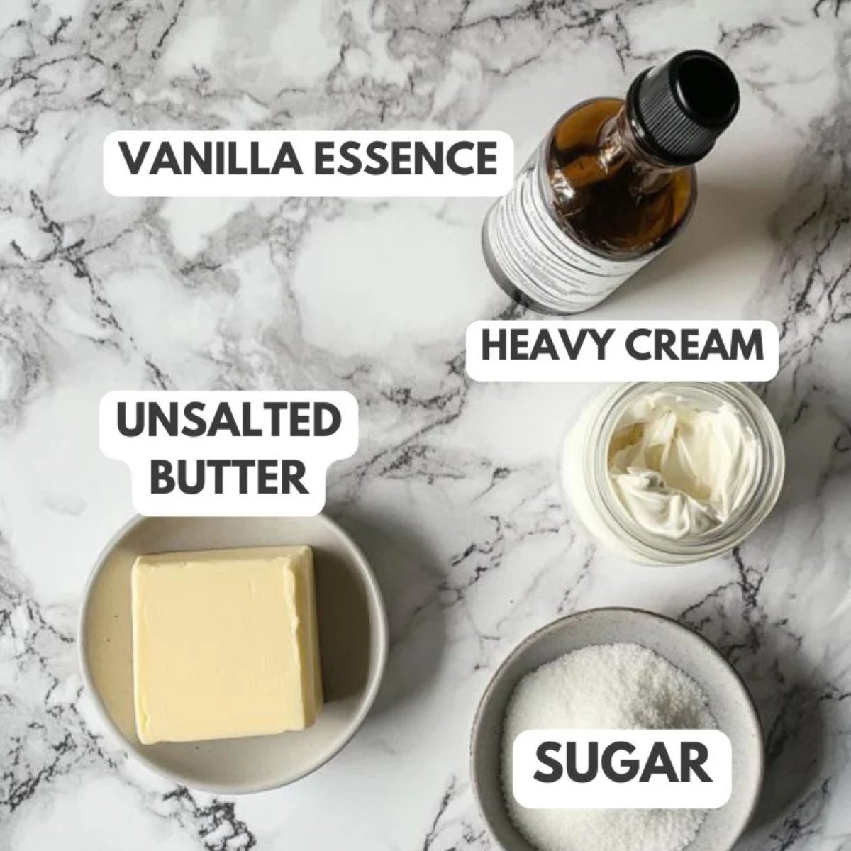 Vanilla essence, unsalted butter, heavy cream and sugar on a grey marble table.