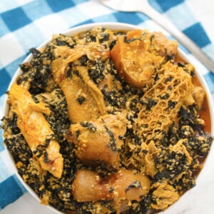 efo elegusi in a white bowl with a blue cloth