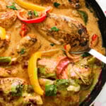 Creamy Cajun chicken fillets and capsicum peppers in a black pan.